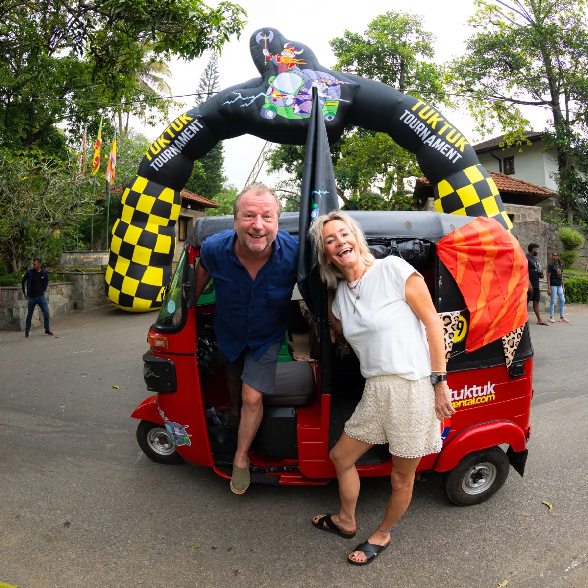 Happy couple with their red tuktuk at starting line